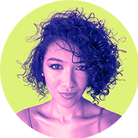 Flávia Santos está de frente, com expressão serena, olhando para a câmera. Tem cabelo curto escuro, cacheado, repartido de lado. A imagem usa um filtro em tons roxos e rosas sobre a pele e o cabelo, contrastando com um fundo verde-limão. Ela veste uma blusa de alça fina.