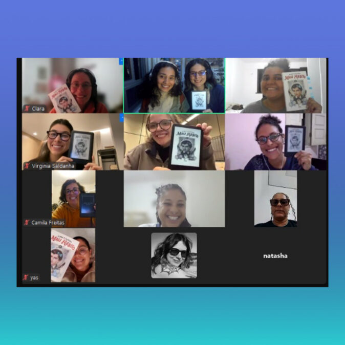 Imagem com fundo em degradê azul e turquesa. Ao centro há uma captura de tela de uma reunião virtual com diversas participantes do Clube do Livro d’AzMina. A maioria aparece sorrindo para a câmera e segurando exemplares físicos ou digitais do livro Mau Hábito, de Alana S. Portero.
As participantes aparecem organizadas em uma grade de vídeo, cada uma em sua própria janela. Algumas usam óculos e fones de ouvido; outras exibem o livro próximo ao rosto. Os ambientes ao fundo são domésticos, com paredes claras e iluminação suave. A imagem transmite um clima de troca, leitura coletiva e celebração do encontro literário.